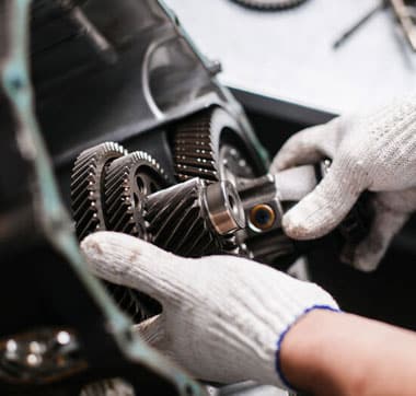Technician with white gloves placing components in transmission during automatic transmission repair.